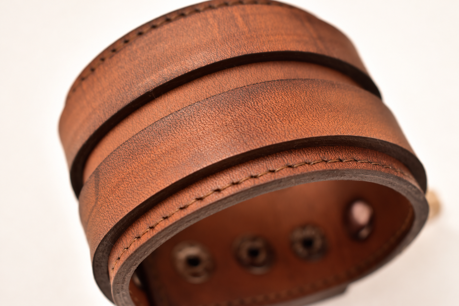 Core Madera Vieja de GAIA ATELIER, vista macro de la pulsera de cuero con costuras y ojales metálicos